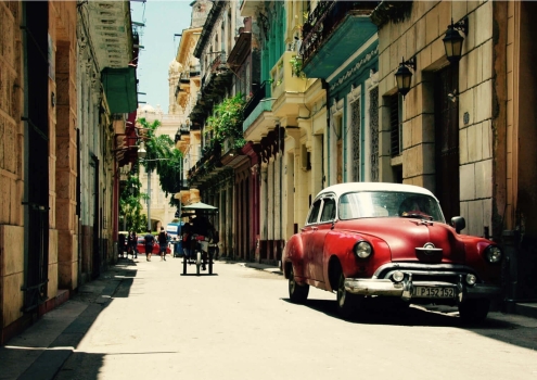 Oldtimer en fietstaxi in straatje Havana, Cuba