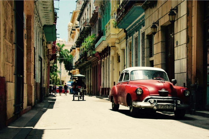 Oldtimer en fietstaxi in straatje Havana, Cuba Oldtimer en fietstaxi in straatje Havana, Cuba
