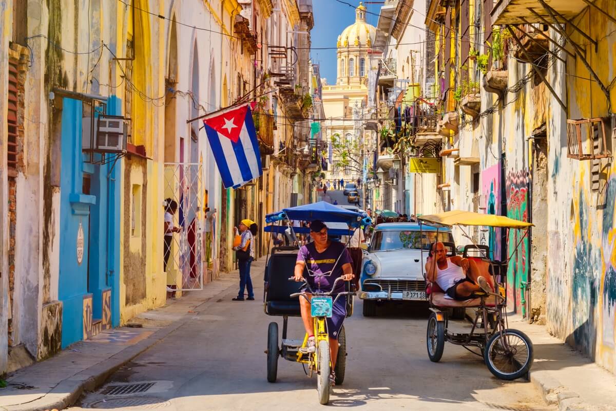 Bici taxis y auto antiguo en una calle de la Habana traslados en Cuba